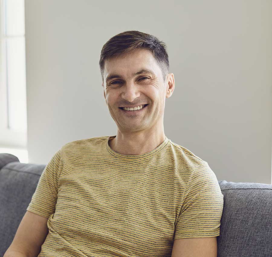 Geschäftsmann im lässigen T-Shirt schaut ernst in die Kamera zu Hause im Büro